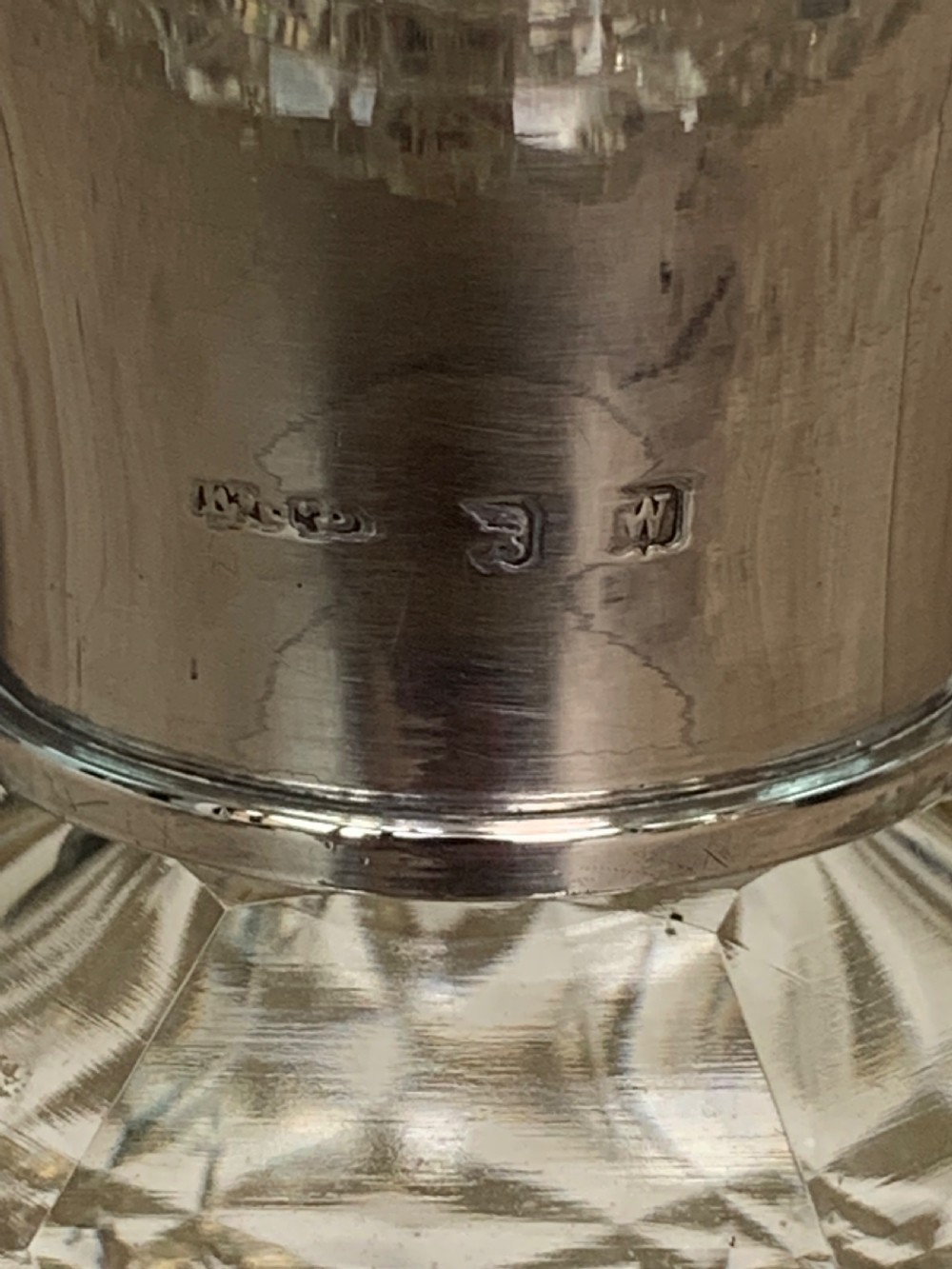A spherical clear cut glass scent bottle featuring diamond patterns and a polished sterling silver neck collar and lid. View V