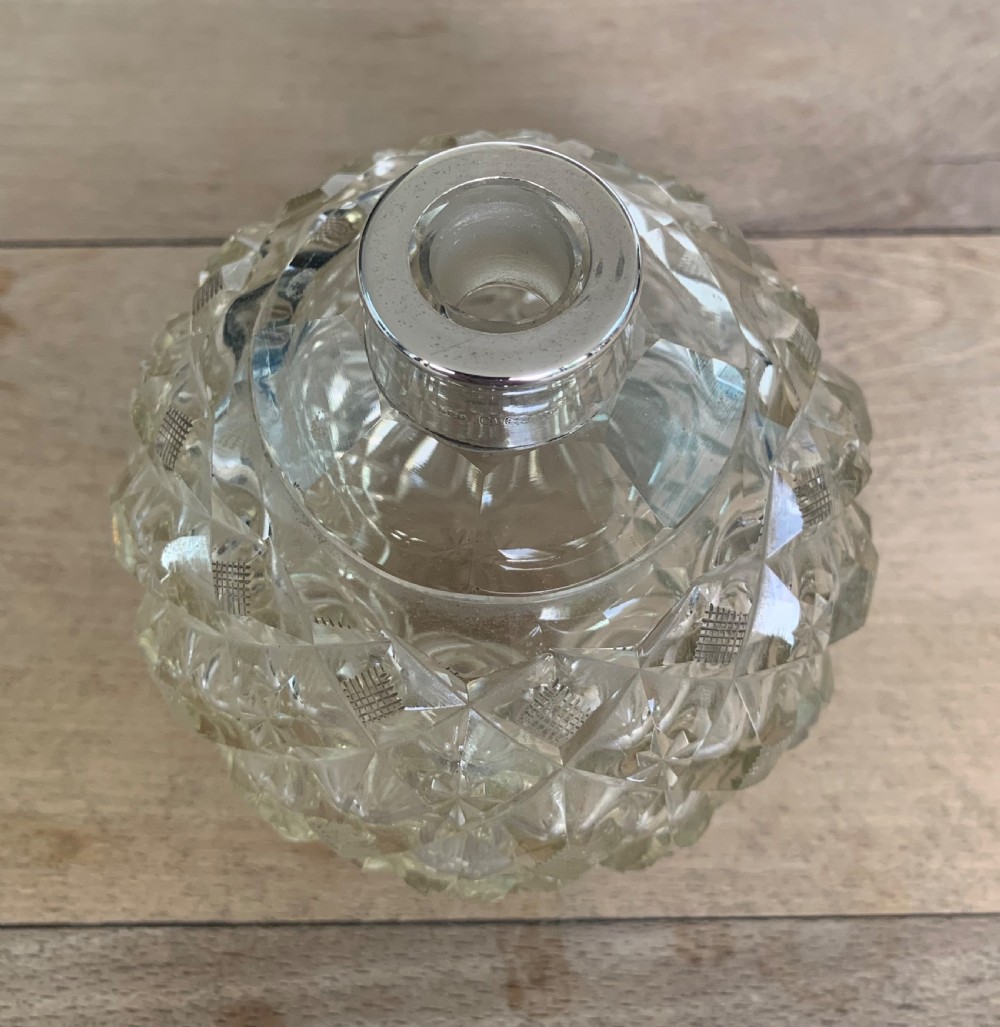 A spherical clear cut glass scent bottle featuring diamond patterns and a polished sterling silver neck collar and lid. View VI