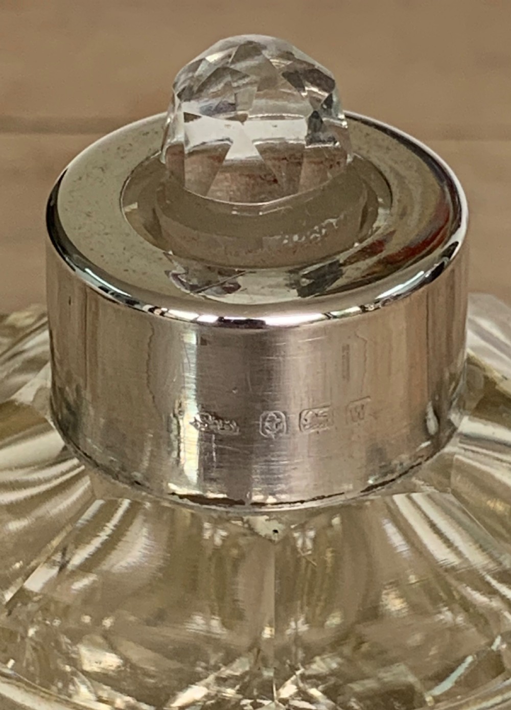 A spherical clear cut glass scent bottle featuring diamond patterns and a polished sterling silver neck collar and lid. View VII