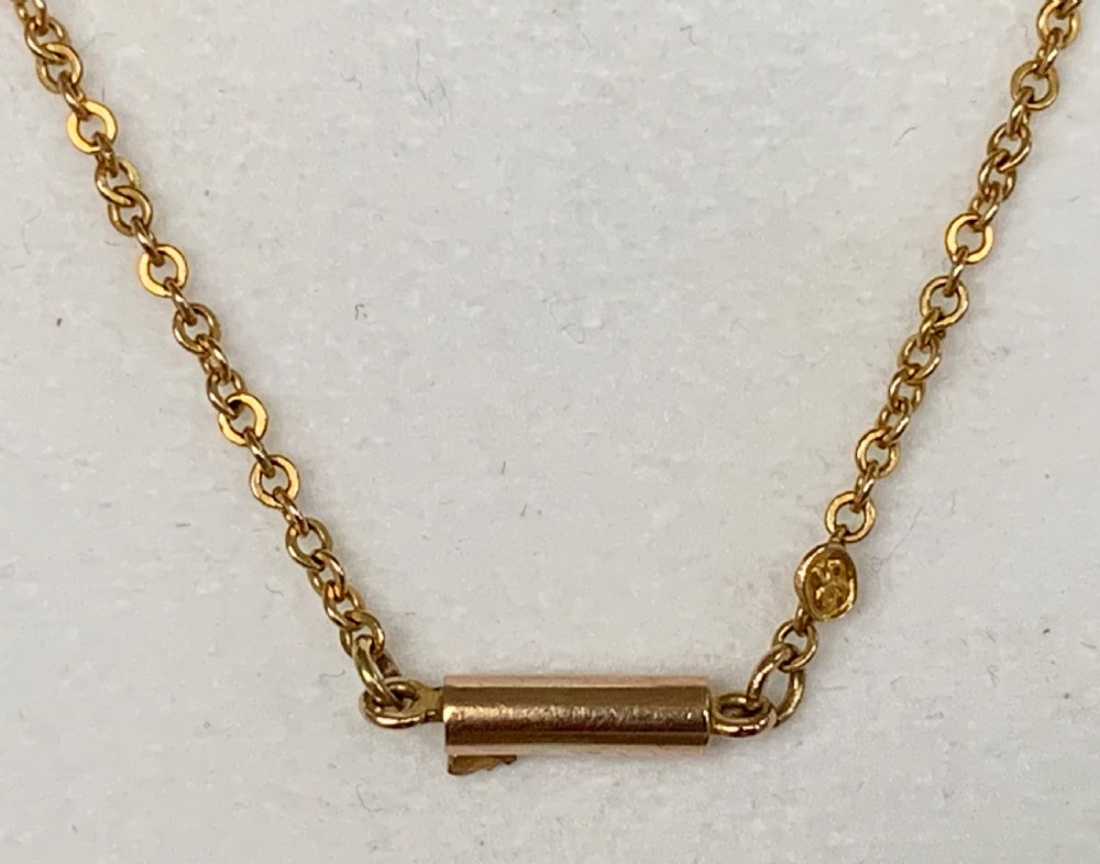 An Edwardian 9ct yellow gold drop necklace featuring a round light blue gemstone linked to a pear-cut gemstone in an openwork frame. View XI