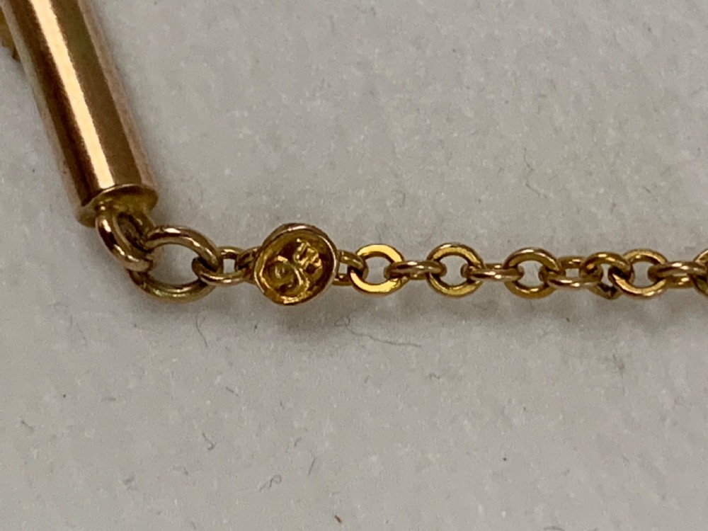 An Edwardian 9ct yellow gold drop necklace featuring a round light blue gemstone linked to a pear-cut gemstone in an openwork frame. View XII