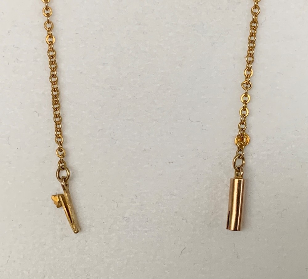 An Edwardian 9ct yellow gold drop necklace featuring a round light blue gemstone linked to a pear-cut gemstone in an openwork frame. View XIII