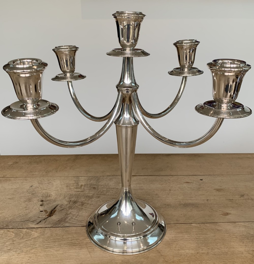 A polished silver candelabra featuring a central candle socket surrounded by four sweeping curved branches resting on a stepped round base. View II