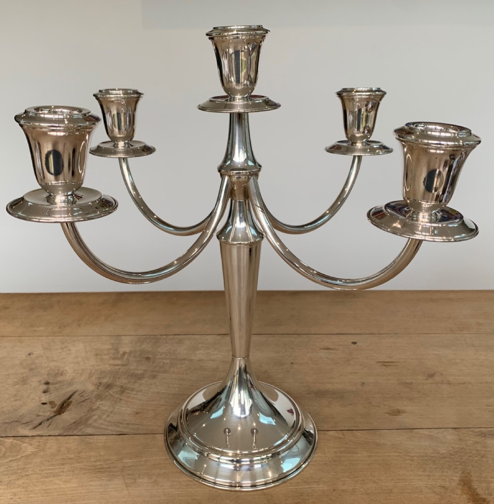 A polished silver candelabra featuring a central candle socket surrounded by four sweeping curved branches resting on a stepped round base. View III