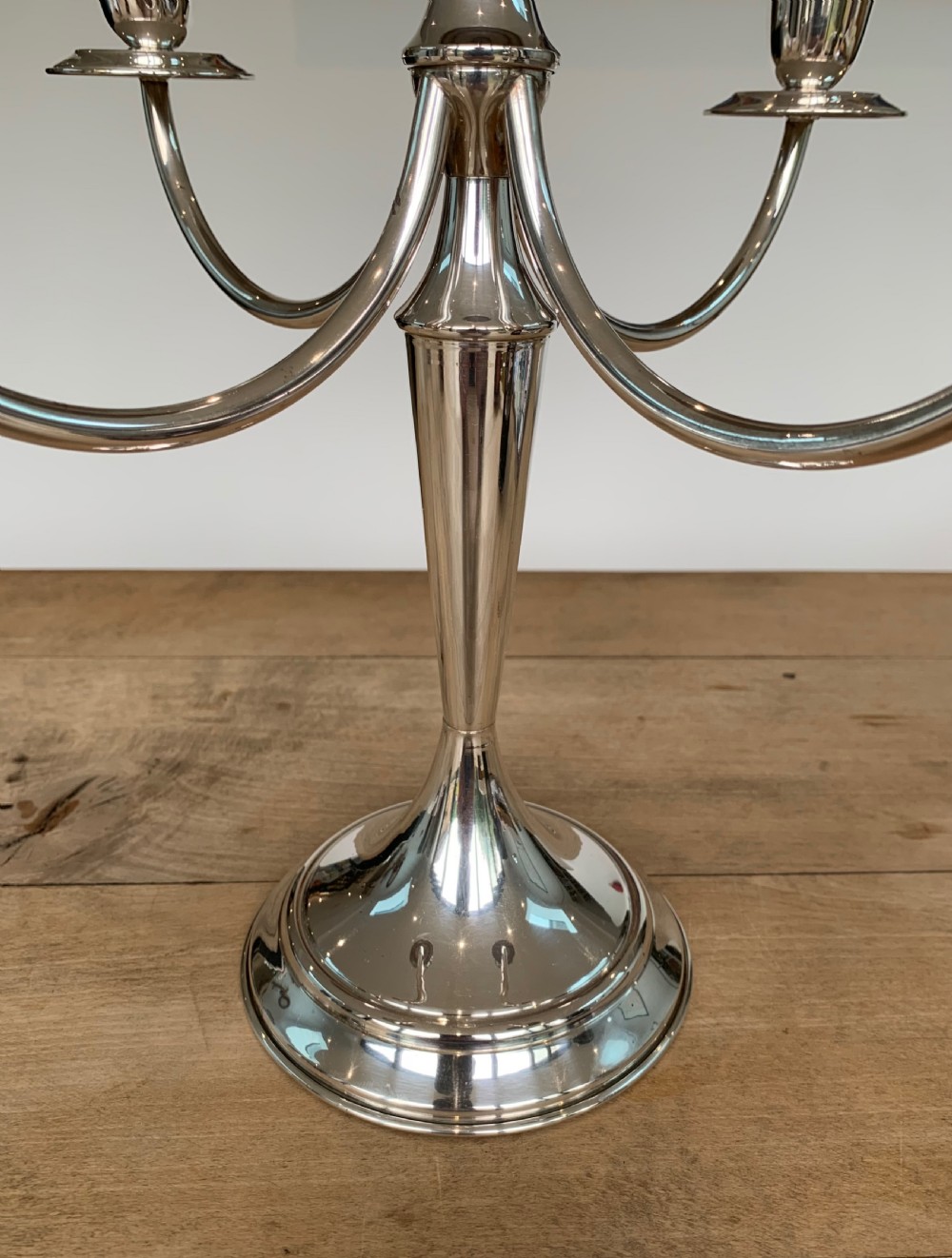 A polished silver candelabra featuring a central candle socket surrounded by four sweeping curved branches resting on a stepped round base. View VII