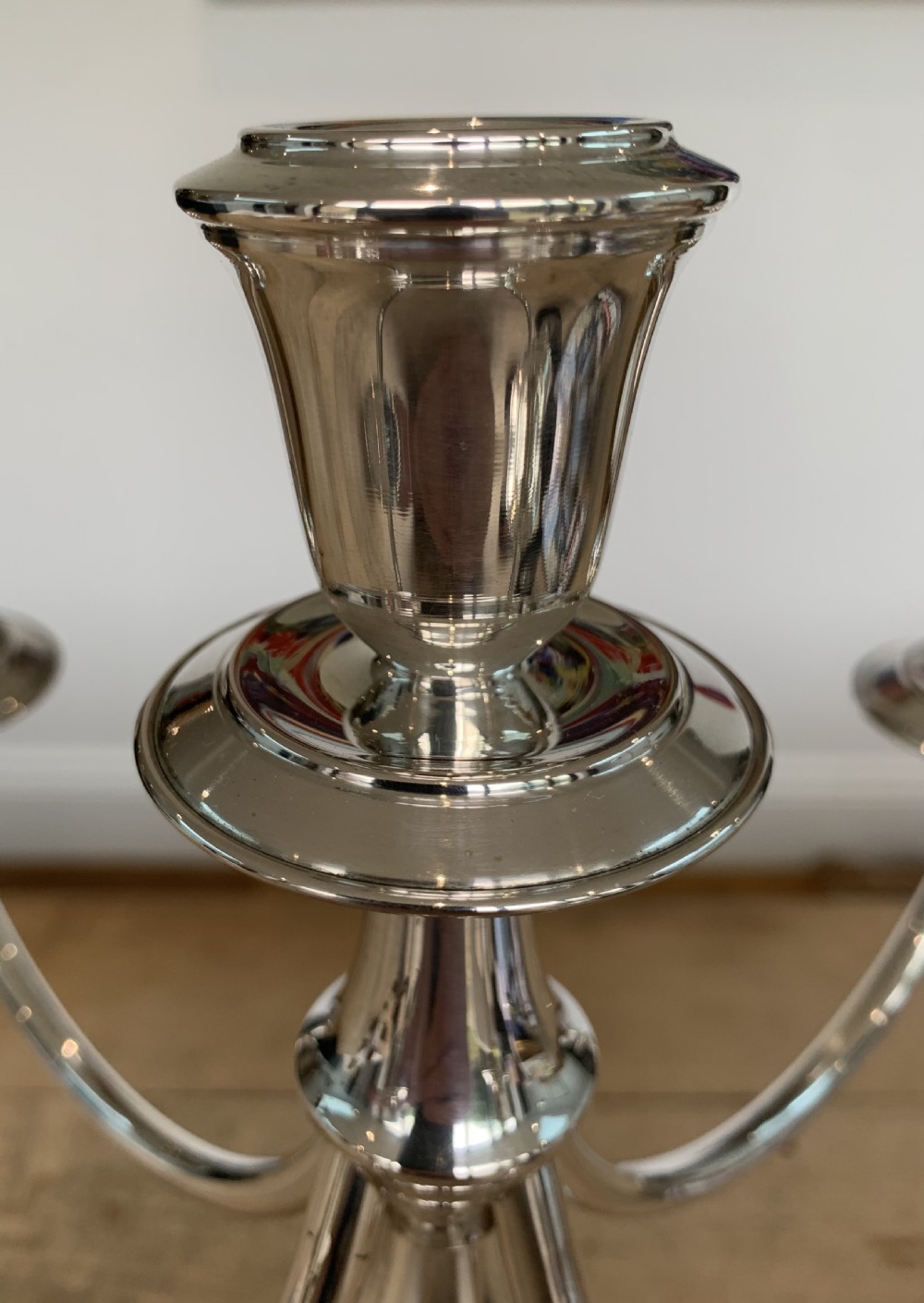 A polished silver candelabra featuring a central candle socket surrounded by four sweeping curved branches resting on a stepped round base. View IX