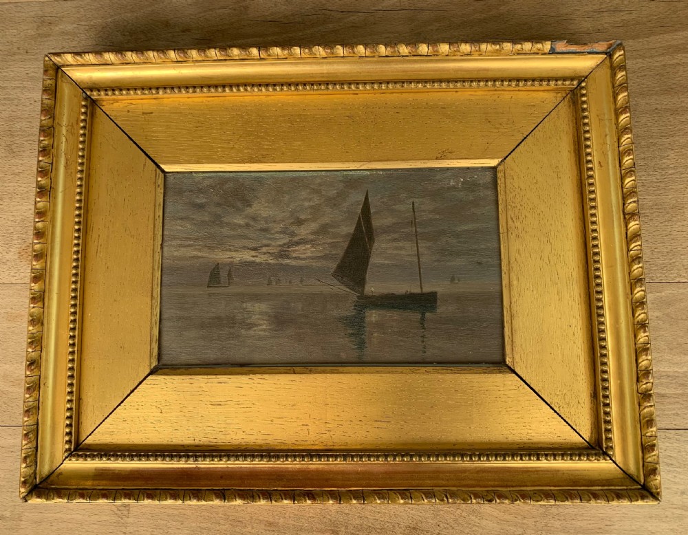 A 19th-century oil painting on board depicting sailing vessels on calm waters under an overcast sky, framed in a wide gilt frame. View IX