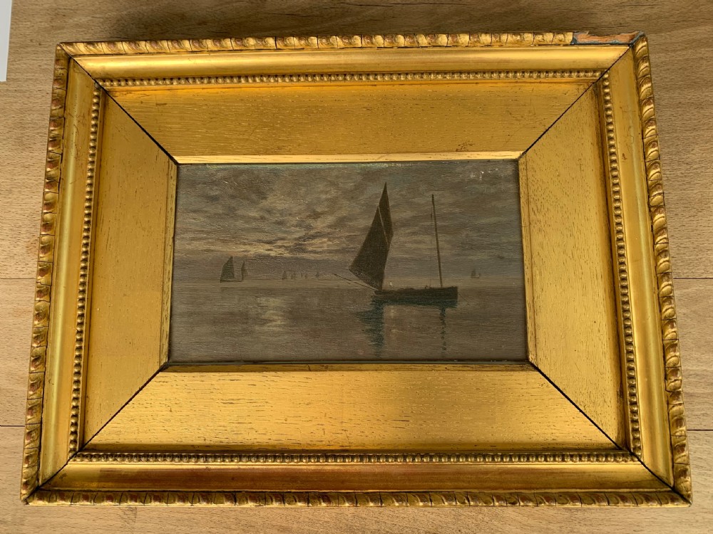 A 19th-century oil painting on board depicting sailing vessels on calm waters under an overcast sky, framed in a wide gilt frame. View X