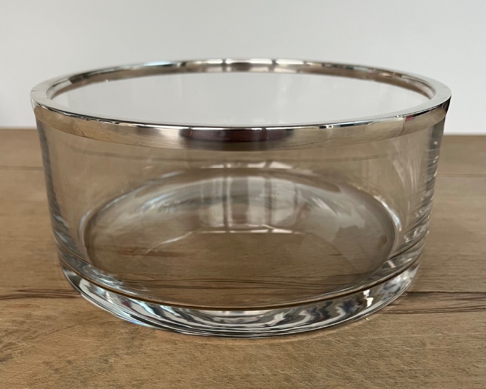 A cylindrical clear glass bowl featuring a smooth polished sterling silver rim around the top edge.
