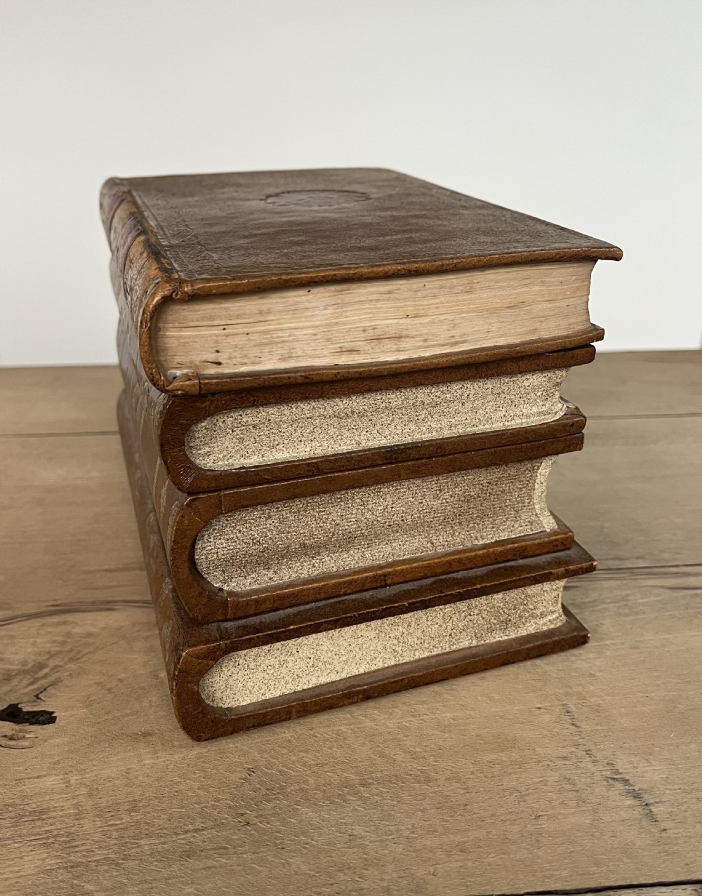 An open vintage warm brown leather box disguised as a stack of two gold-tooled books, featuring a fabric-lined interior with a brass support mechanism. View III