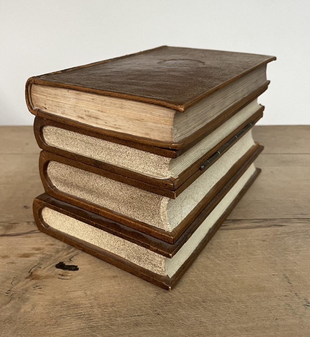 An open vintage warm brown leather box disguised as a stack of two gold-tooled books, featuring a fabric-lined interior with a brass support mechanism. View IV