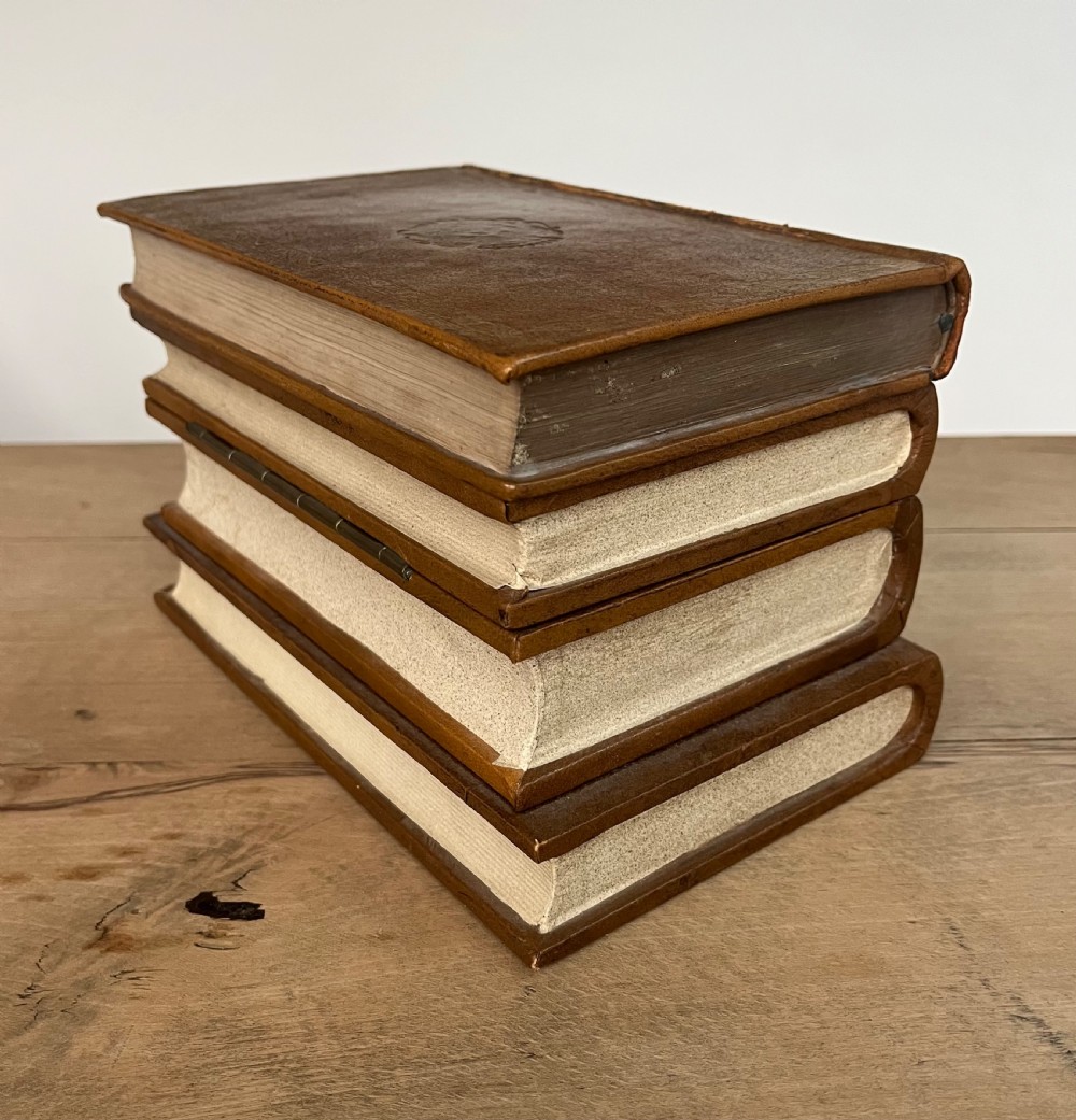 An open vintage warm brown leather box disguised as a stack of two gold-tooled books, featuring a fabric-lined interior with a brass support mechanism. View VI