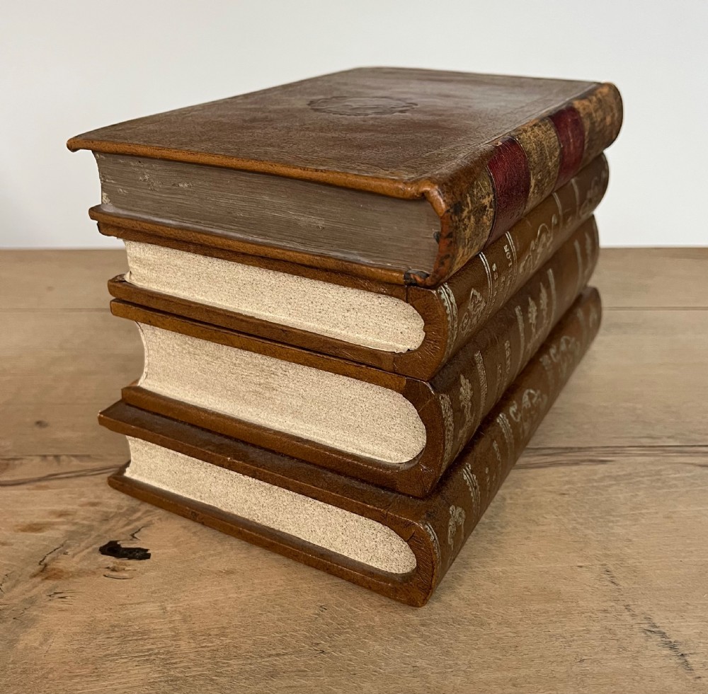 An open vintage warm brown leather box disguised as a stack of two gold-tooled books, featuring a fabric-lined interior with a brass support mechanism. View VII
