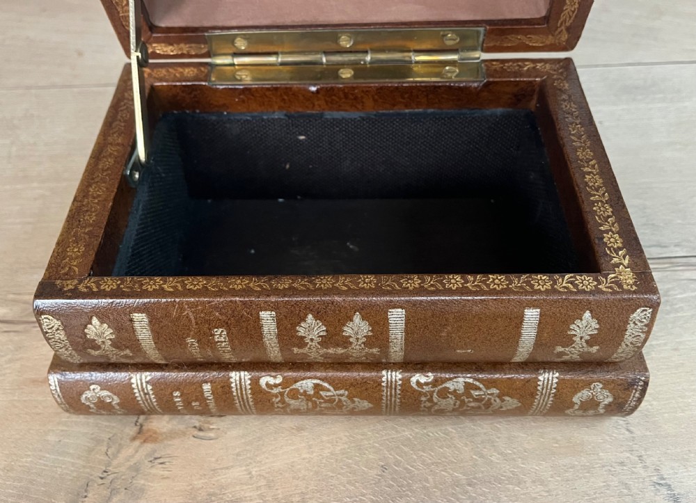An open vintage warm brown leather box disguised as a stack of two gold-tooled books, featuring a fabric-lined interior with a brass support mechanism. View XI