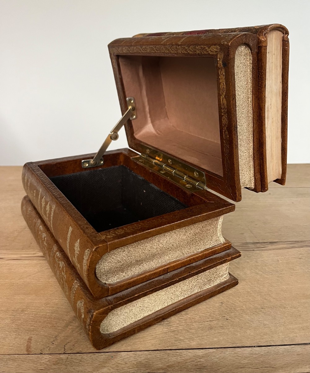 An open vintage warm brown leather box disguised as a stack of two gold-tooled books, featuring a fabric-lined interior with a brass support mechanism. View XII