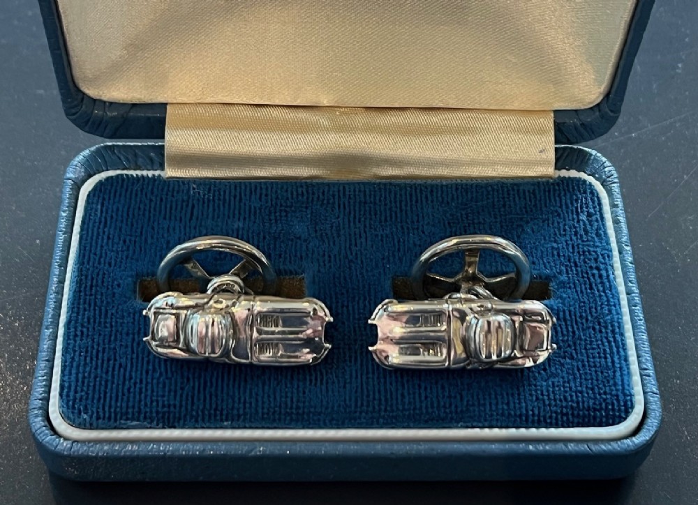 A pair of sterling silver cufflinks shaped in the detailed form of Jaguar E-Type sports cars with three-spoke steering wheel backings.