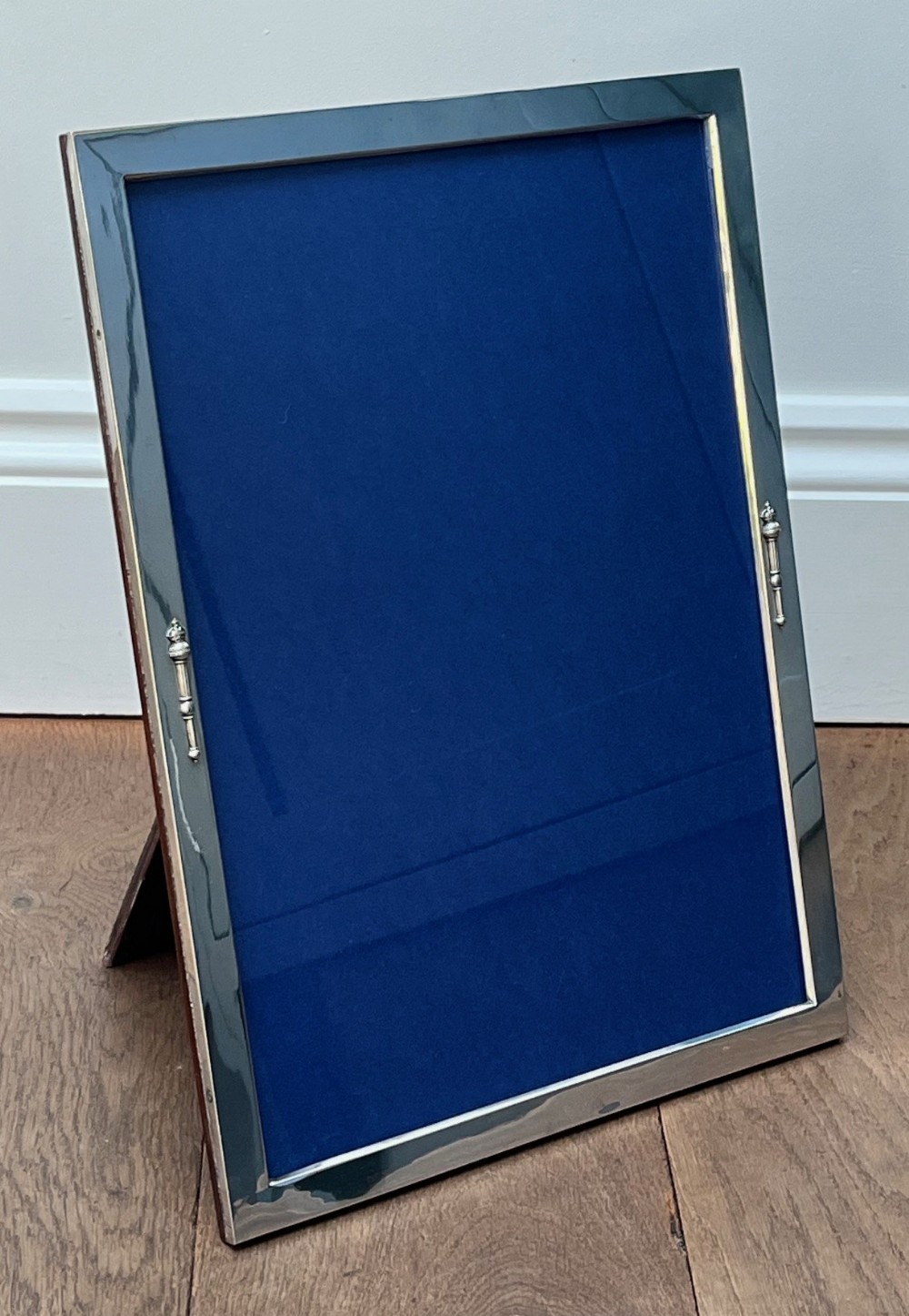 A large rectangular standing 800 silver photograph frame with a royal blue insert and small decorative side handles.