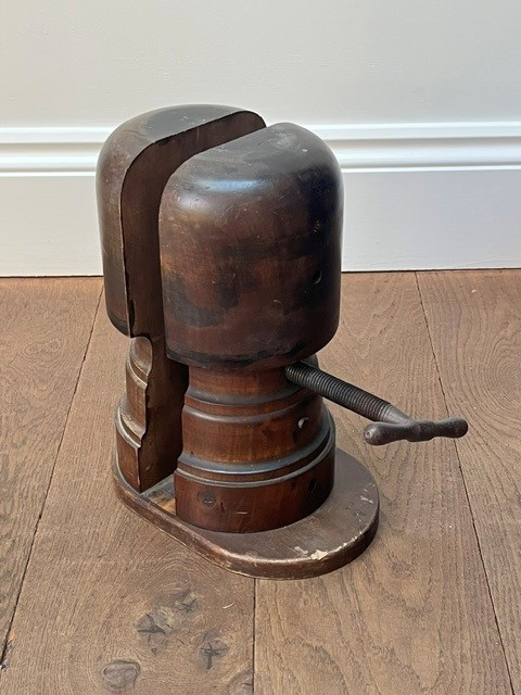 A nineteenth-century dark carved wooden hat stretcher featuring a split block mechanism operated by a threaded metal turn screw, set on an oval base. View VIII