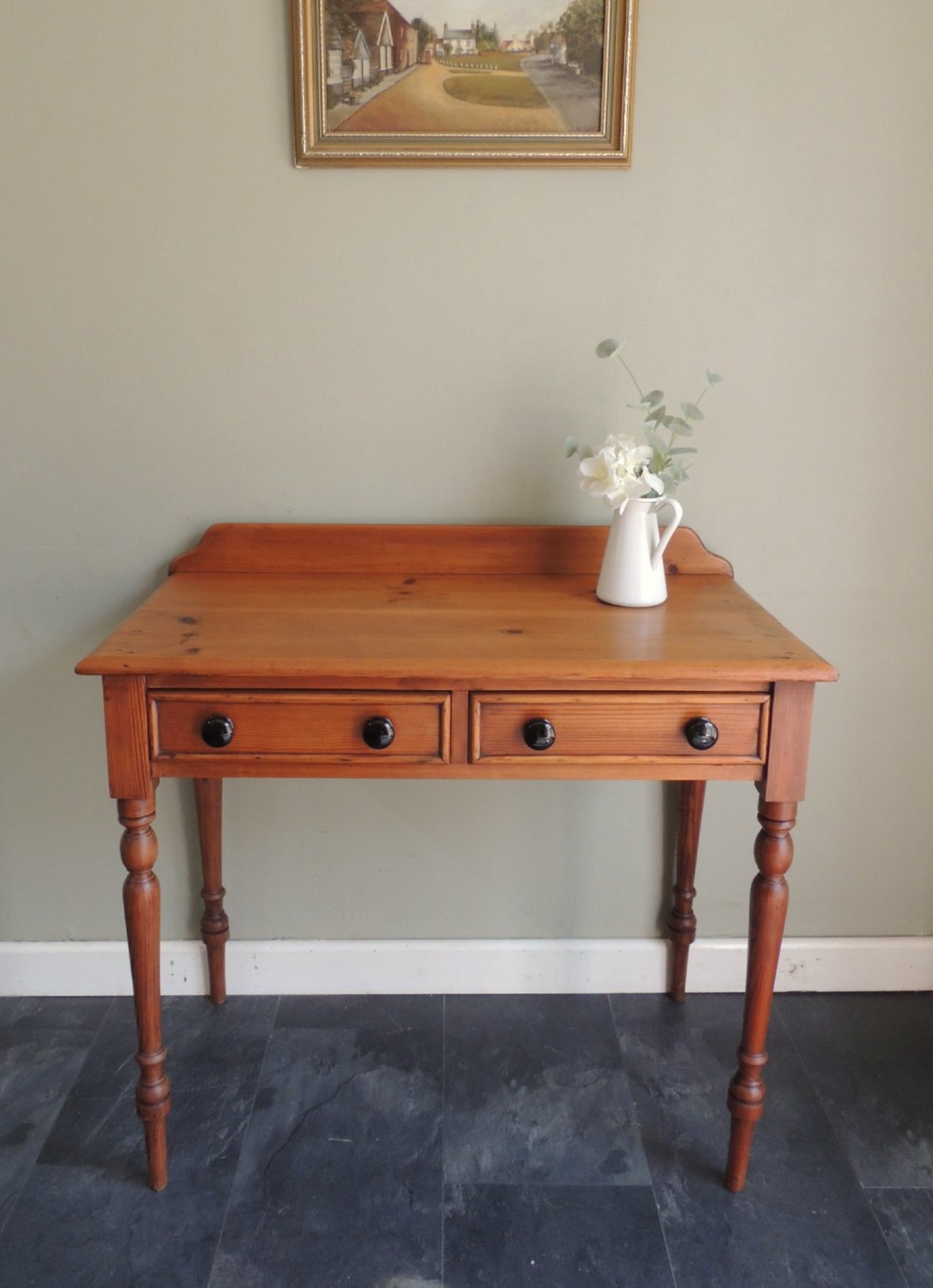 A Victorian solid pine hall table featuring a low gallery backboard, two drawers with dark round knobs, and four turned legs. View III