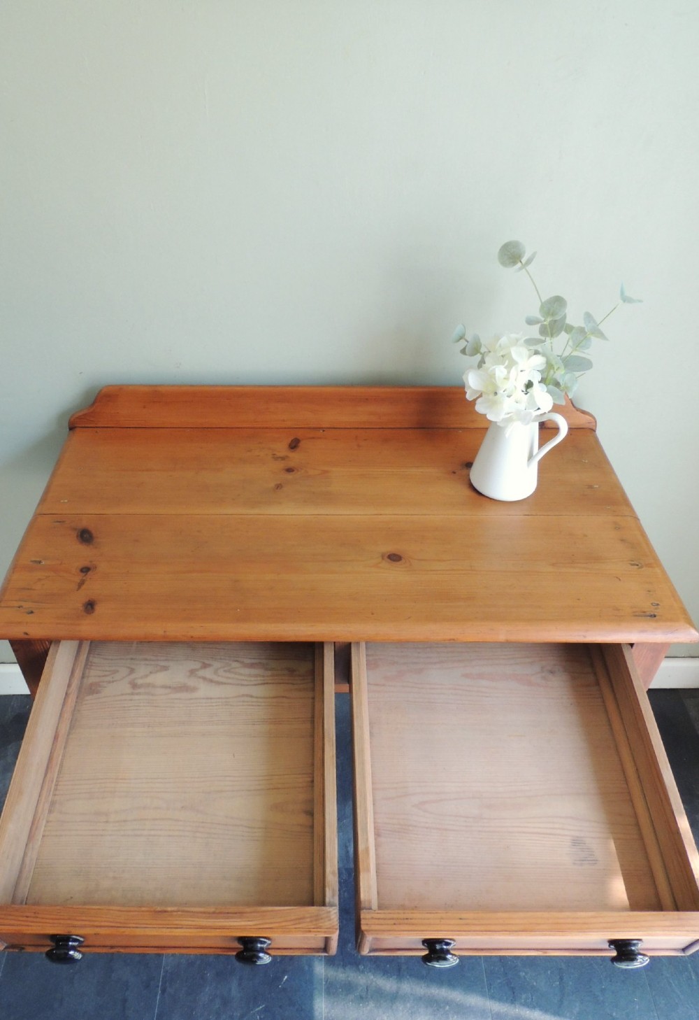 A Victorian solid pine hall table featuring a low gallery backboard, two drawers with dark round knobs, and four turned legs. View VIII