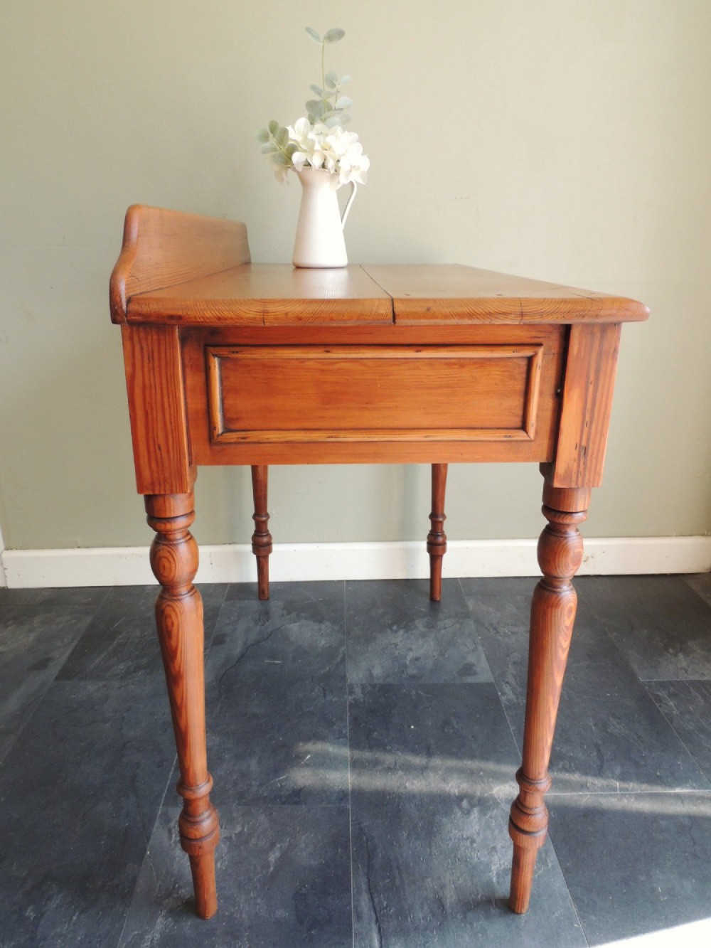A Victorian solid pine hall table featuring a low gallery backboard, two drawers with dark round knobs, and four turned legs. View IX