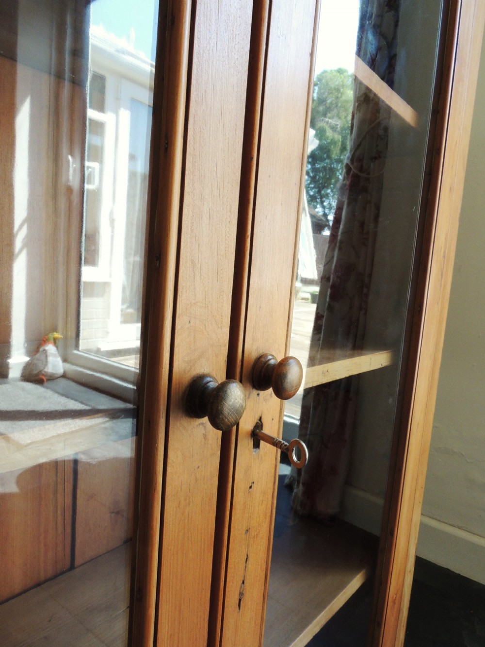 A Victorian solid pine glazed display cabinet featuring two full-length glass doors, wooden turned knobs, interior shelves, and a moulded top cornice. View IV