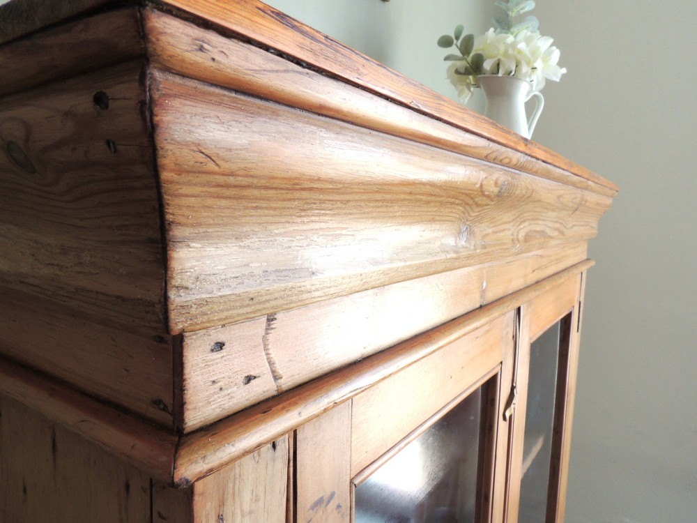 A Victorian solid pine glazed display cabinet featuring two full-length glass doors, wooden turned knobs, interior shelves, and a moulded top cornice. View V
