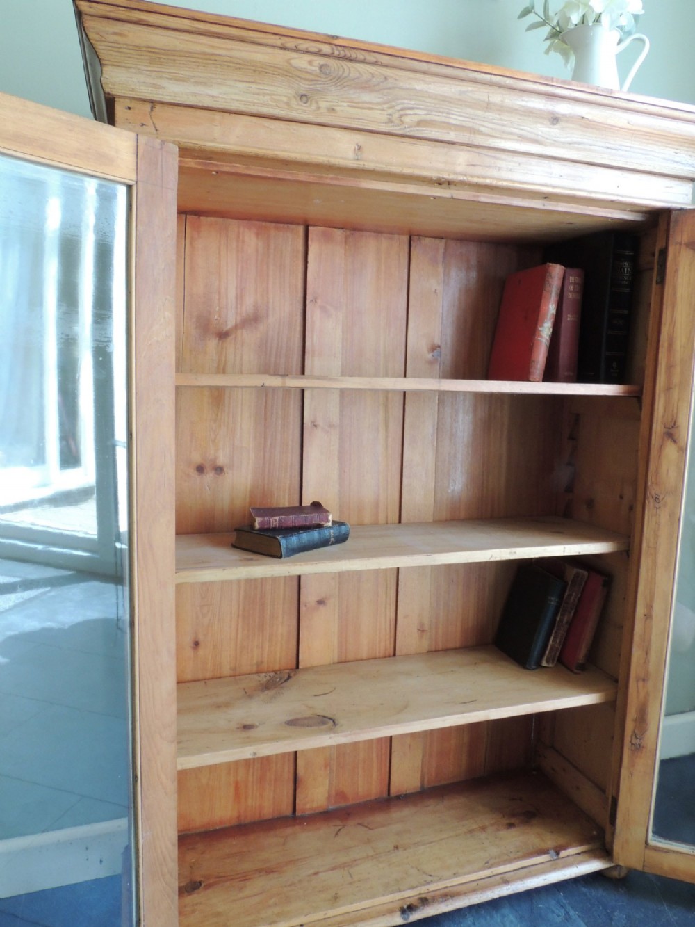 A Victorian solid pine glazed display cabinet featuring two full-length glass doors, wooden turned knobs, interior shelves, and a moulded top cornice. View IX