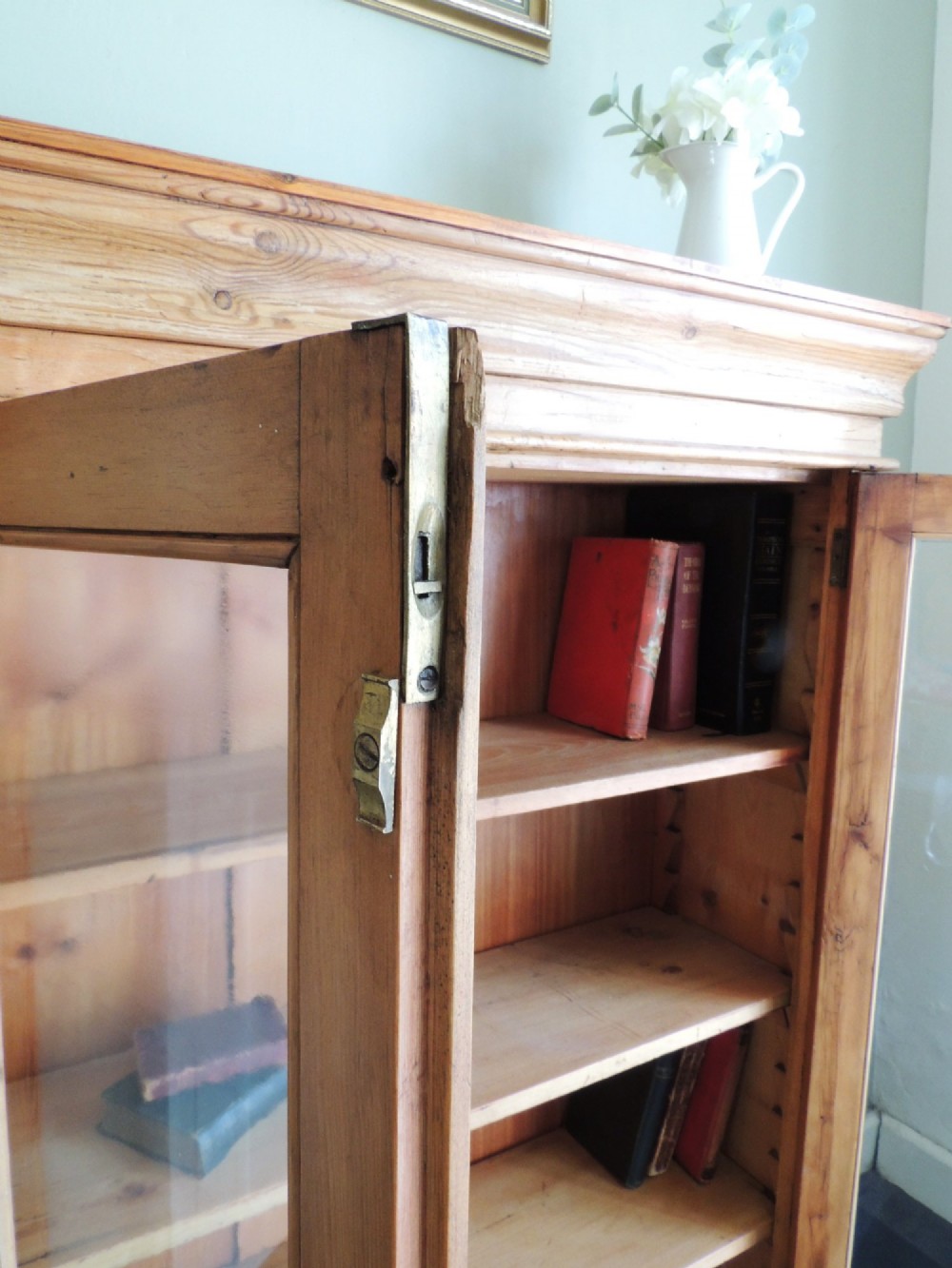 A Victorian solid pine glazed display cabinet featuring two full-length glass doors, wooden turned knobs, interior shelves, and a moulded top cornice. View X