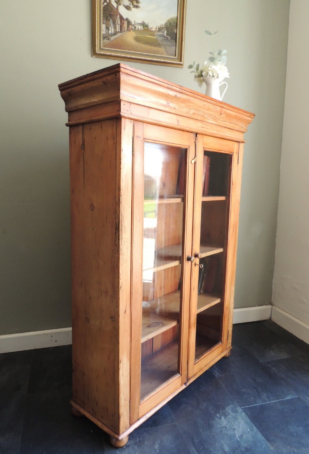 A Victorian solid pine glazed display cabinet featuring two full-length glass doors, wooden turned knobs, interior shelves, and a moulded top cornice. View XI