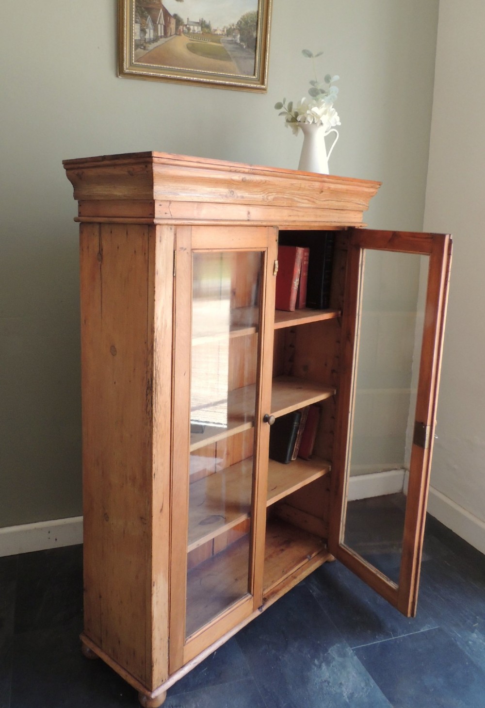 A Victorian solid pine glazed display cabinet featuring two full-length glass doors, wooden turned knobs, interior shelves, and a moulded top cornice. View XII