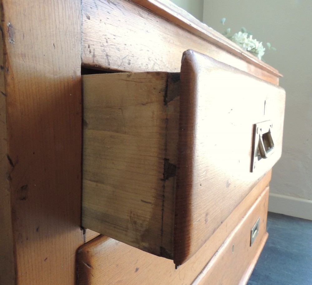 A Victorian solid pine chest of drawers featuring two short drawers over two long drawers fitted with flush brass handles. View IV
