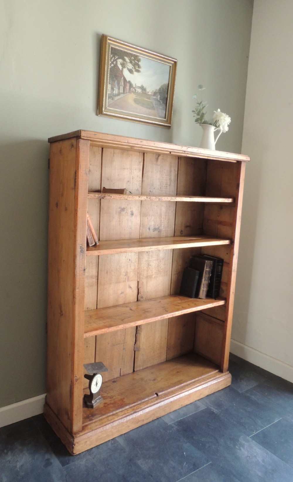 A tall Victorian open-front pine bookcase featuring four spacious shelves and a planked backboard resting on a solid plinth base.