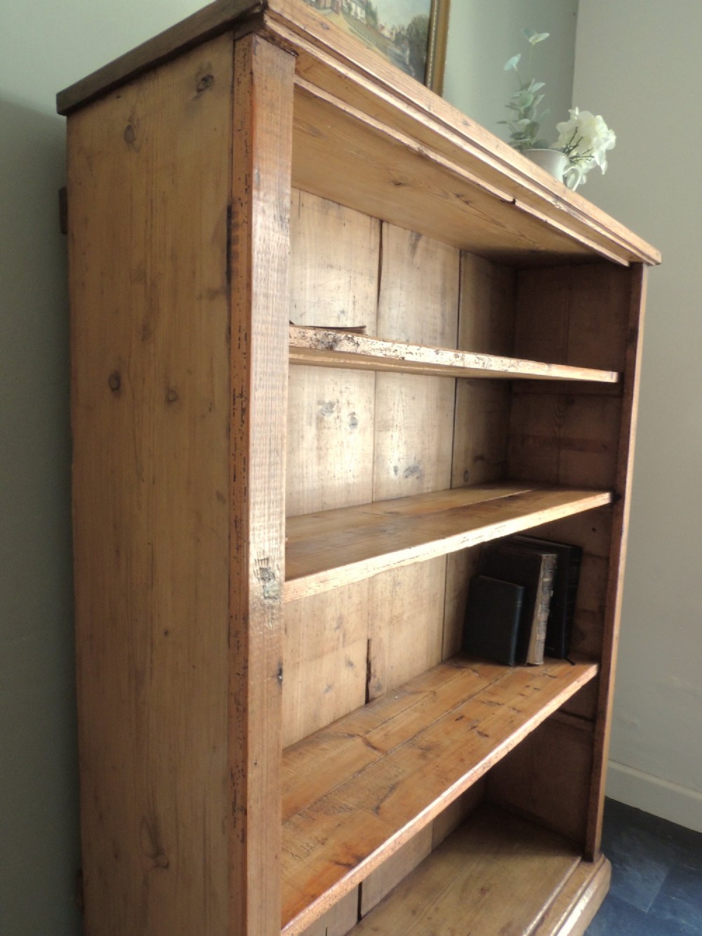A tall Victorian open-front pine bookcase featuring four spacious shelves and a planked backboard resting on a solid plinth base. View V