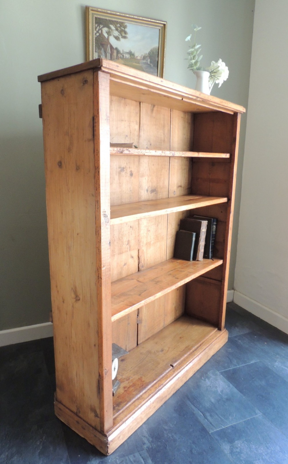 A tall Victorian open-front pine bookcase featuring four spacious shelves and a planked backboard resting on a solid plinth base. View XIII