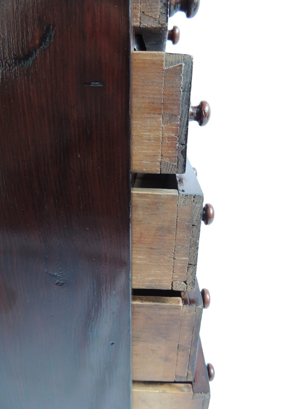 A dark stained pine Victorian miniature chest of drawers featuring six drawers with turned wooden knobs and a shaped plinth base. View IX