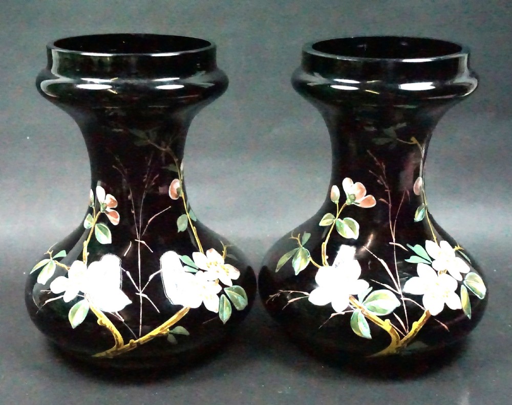 A pair of dark amethyst glass bulb vases decorated with hand-painted white and pink wild rose enamel motifs.