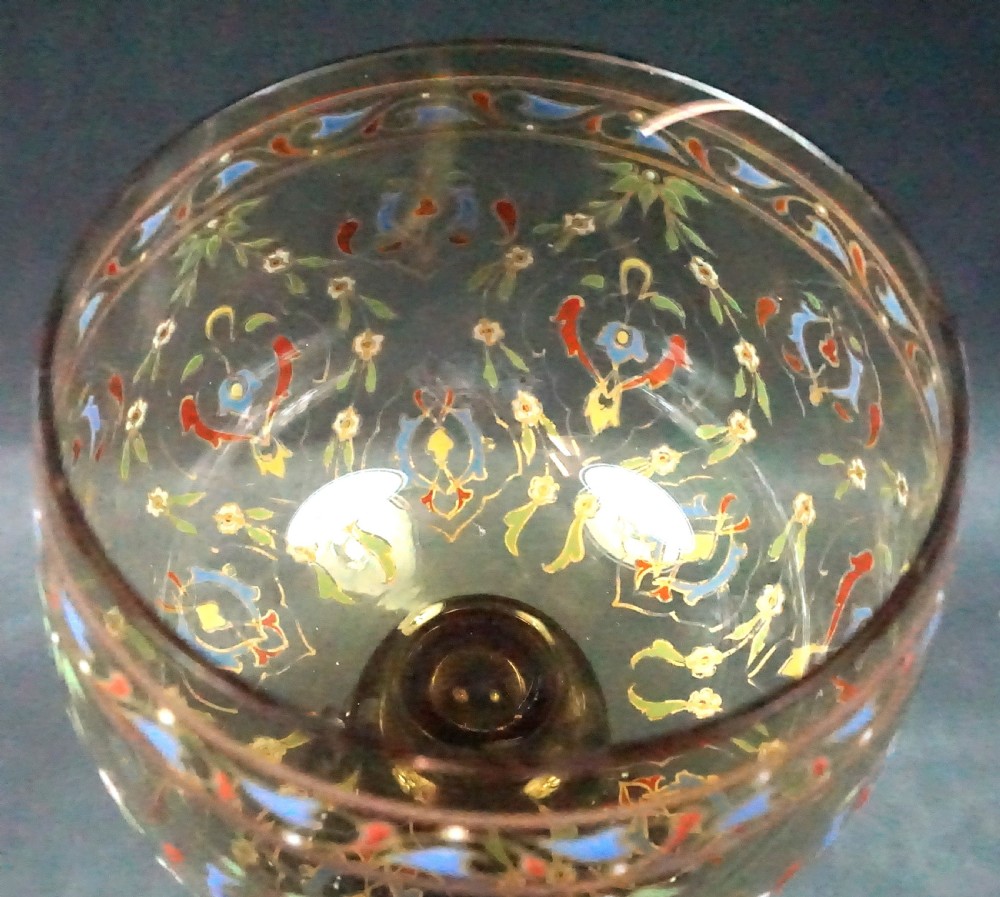 An antique Bohemian pale green glass roemer featuring elaborate polychrome enamel scrollwork around the bowl, applied prunts on the stem, and a frilled base. View II