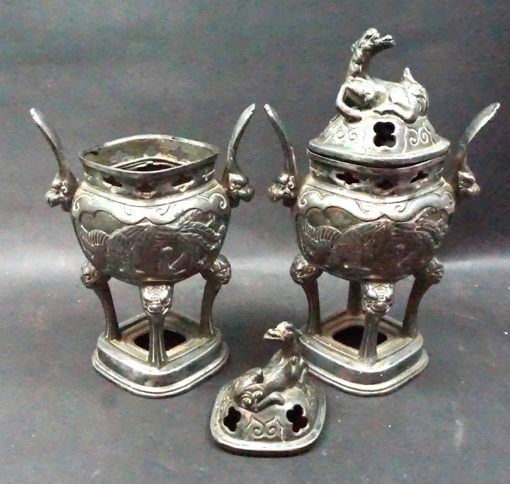 A pair of late Qing Dynasty Chinese antimony metal censers featuring relief dragon panels, animal finials, and pierced lids. View II