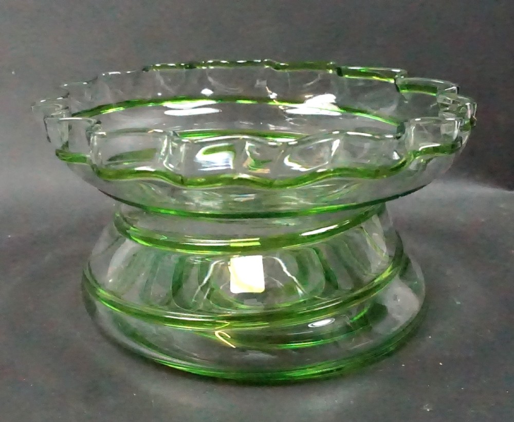 An English Arts and Crafts clear glass centerpiece bowl featuring a crimped rim and green glass trail decoration around the rim and pedestal base.