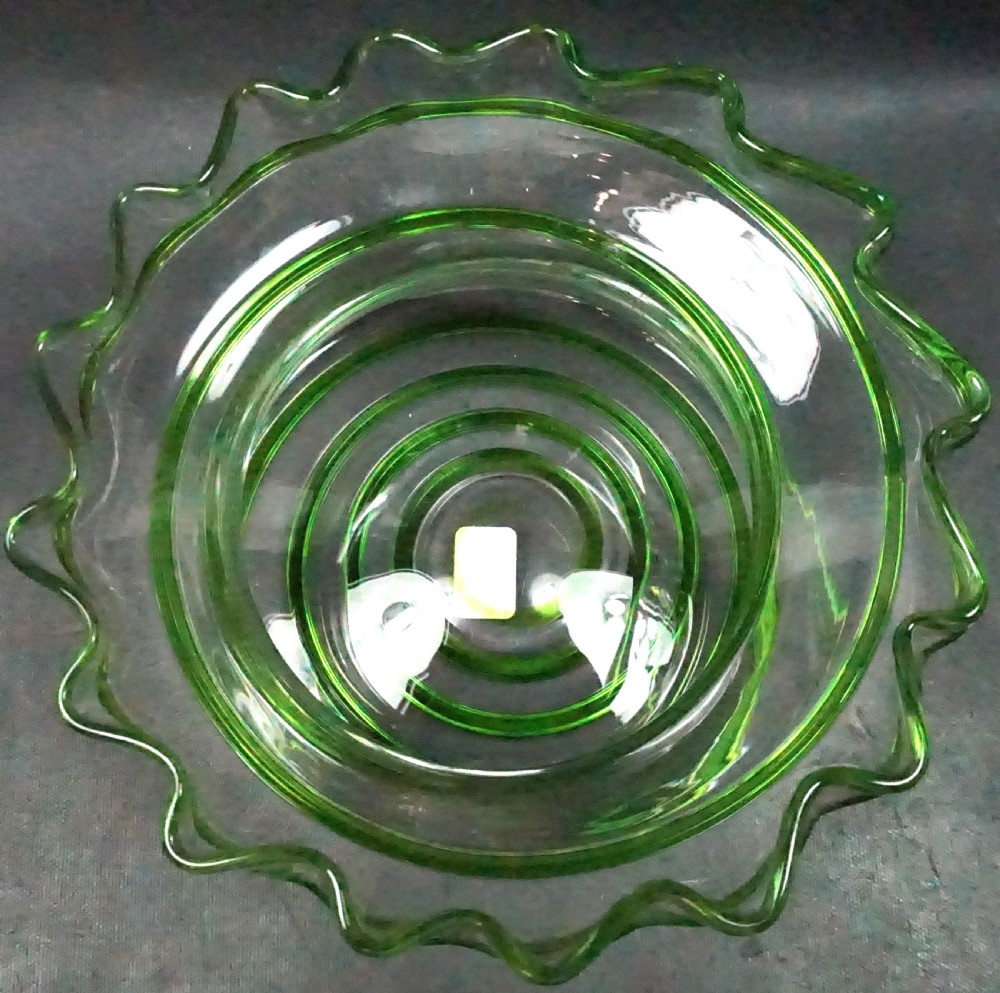 An English Arts and Crafts clear glass centerpiece bowl featuring a crimped rim and green glass trail decoration around the rim and pedestal base. View II