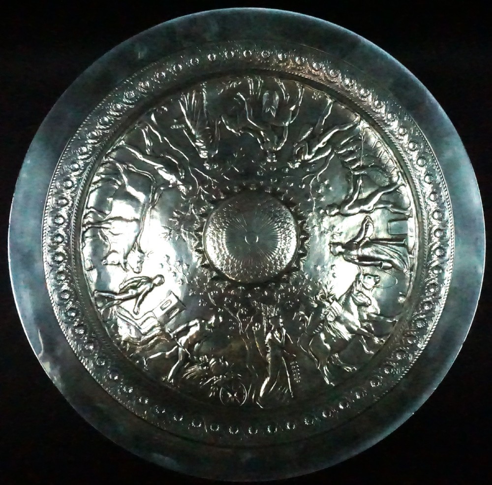 A circular Victorian silver-plated bronze tazza featuring detailed classical relief artwork depicting mythological figures surrounding a central raised boss.