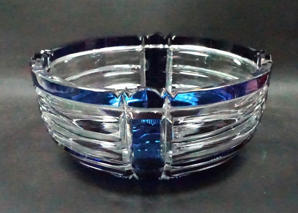 A circular Art Deco lead crystal bowl featuring a cobalt blue overlay cut with horizontal lines and vertical geometric facets.
