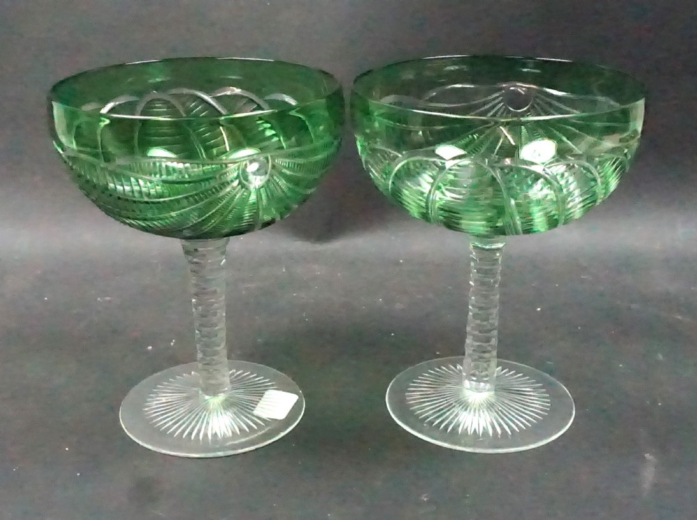 A pair of antique green cut-to-clear crystal champagne coupes featuring faceted stems and starburst cut bases.