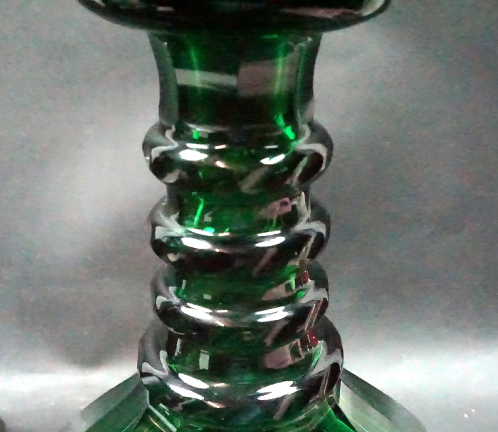 A pair of dark green glass ships decanters featuring broad conical bases with facet cuts, ringed necks, and fitted radial stoppers. View II
