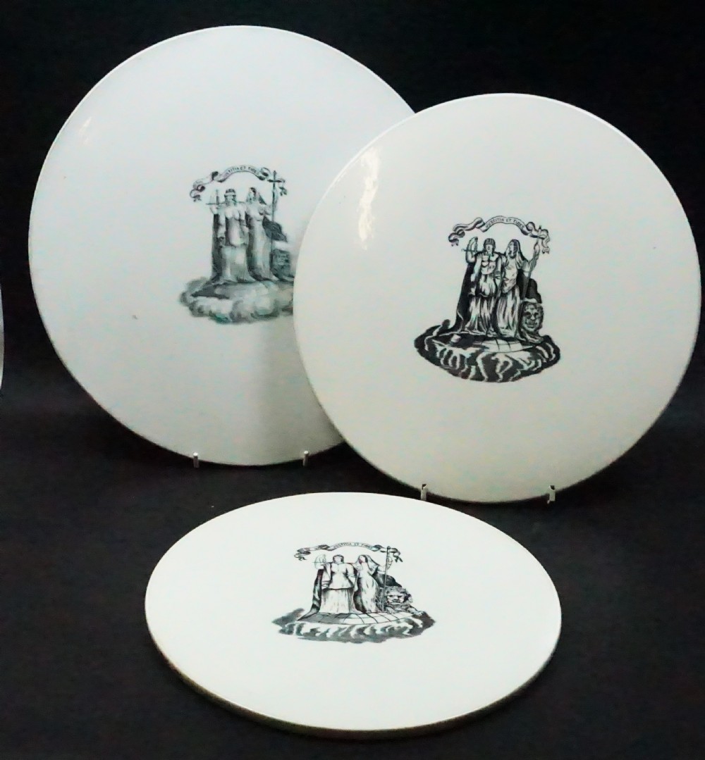 Three circular white ceramic scale pans of varying sizes featuring black transfer-printed justice emblems on their surfaces.