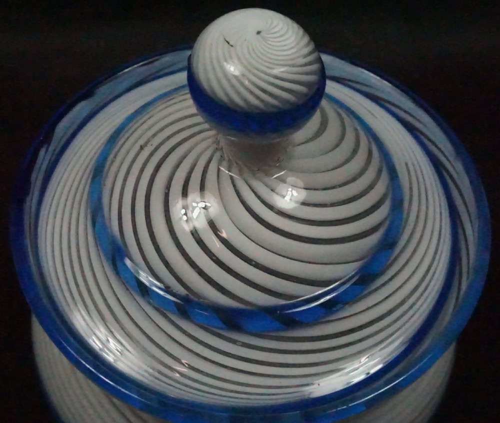 A 19th-century lidded glass sugar bowl crafted with spiralling white latticinio strands and trimmed with cobalt blue cane rims. View II