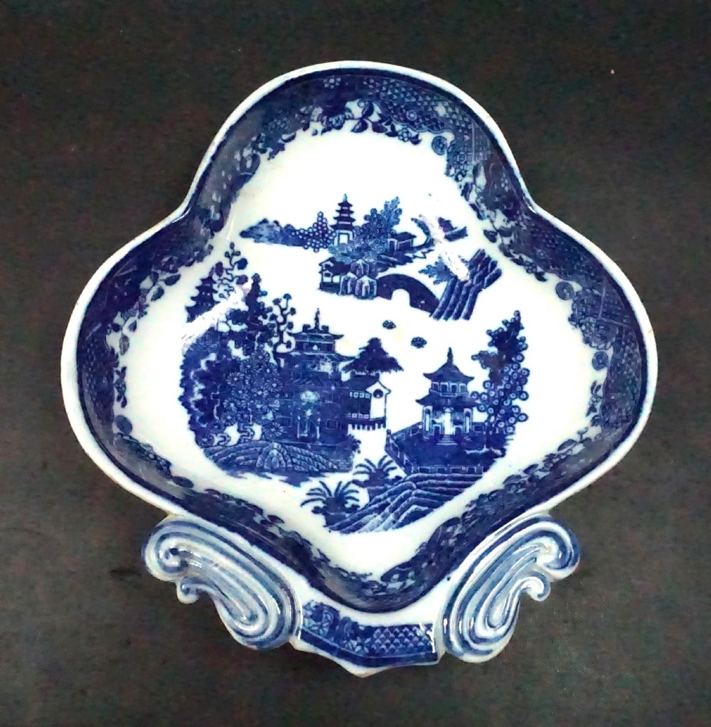 An eighteenth-century lobed ceramic spoon tray featuring cobalt blue transfer-printed chinoiserie pagodas and scroll detailing at the base.
