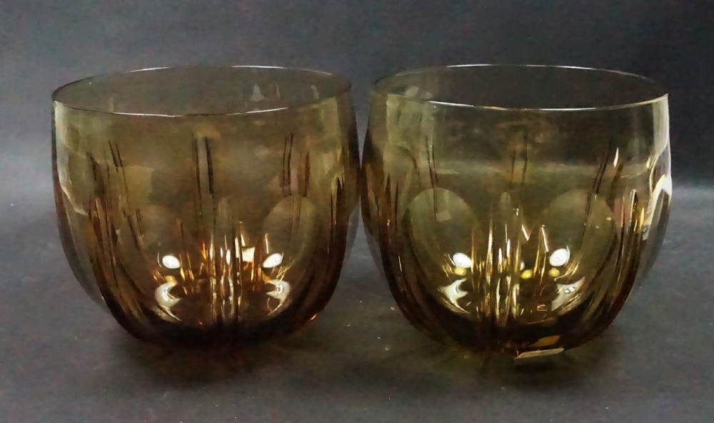 A pair of rounded Georgian amber glass finger bowls featuring vertical cut facets and circular lens cuts around the body.