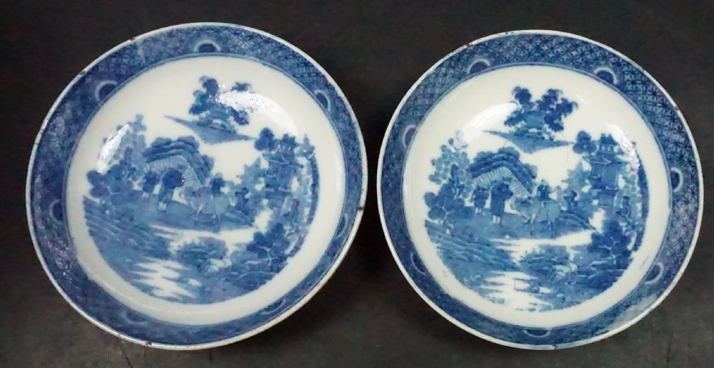 A pair of circular 18th-century English creamware pickle dishes featuring blue underglaze Chinoiserie scenes.